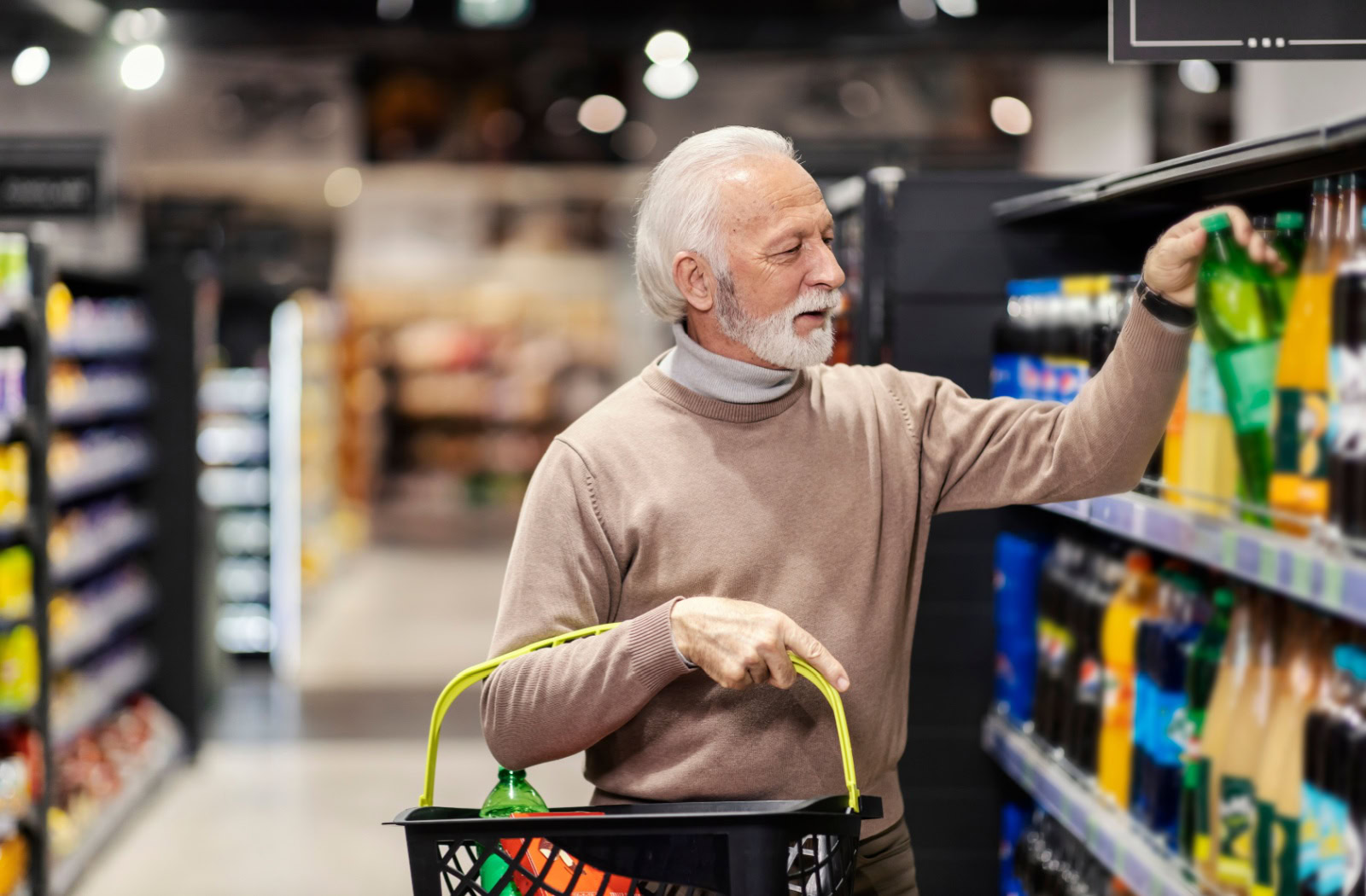 A senior at a clean, well-lit grocery store fills a basket full of pop, adding more sugary drinks to their diet