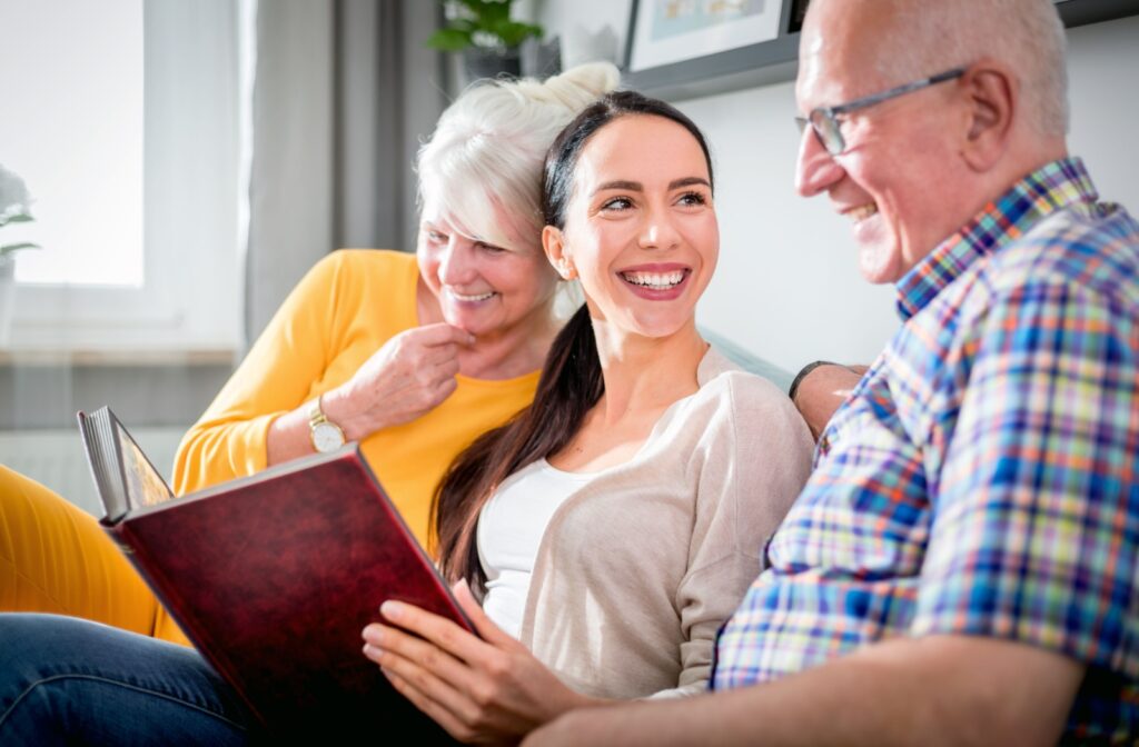 Residents and a visiting loved one share smiles on the community couch, reminiscing over cherished memories in a photo album