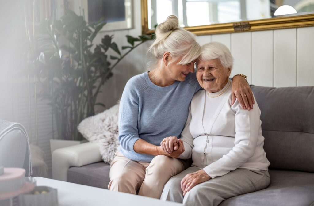 a younger child supports their senior parent. they sit on a couch